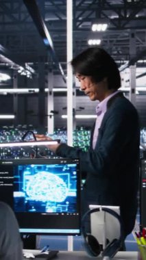 Dikey Veri Merkezi Yöneticisi, sinirsel ağ AI LLM 'lerini izlemek için aygıt kullanan geliştiriciyi denetliyor. Ekip lideri, sunucuların öğrenme işlemini denetleyen işçiler tarafından yapılan işlemi kontrol ediyor.