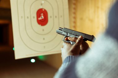 Atış poligonu tesisinde silah tutan adam eğlence amaçlı atış deneyiminin tadını çıkarıyor. Yaklaş. Atış poligonunda silahlarla pratik yapan biri.