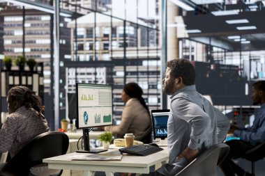 Afrika kökenli Amerikalı bir şirket çalışanı, rahatsız edici bir sandalye ve yanlış bir duruşla çalıştıktan sonra ağrısını hafifletmek için ofiste biraz ara veriyor. İltihap..