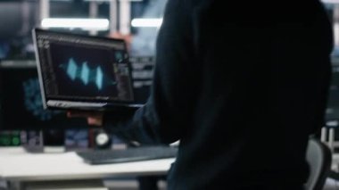 Veri merkezine gelen teknisyen, üretici yapay zeka yardımıyla kodlama yapıyor. BT uzmanı masada oturuyor, yapay zeka üzerinde çalışıyor büyük dil modeli çözme görevleri, kamera A