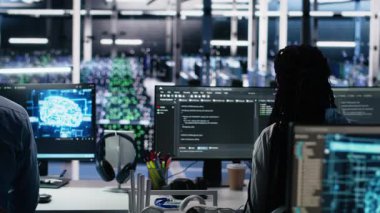 Veri merkezinde beyin fırtınası yapan ekip mühendisleri, bilgisayardaki yapay zeka teşhislerini gözden geçiriyorlar. Sunucu odasında birlikte çalışan bilişim uzmanı ekibi yapay zeka sistemlerini optimize ediyor, kamera A