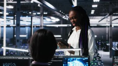 Veri merkezi geliştiricilerinden oluşan bir ekip beyin fırtınası yapıyor, sinir ağı AI LLM 'yi izliyor. Yüksek teknoloji tesisinde çalışan takım arkadaşları sunuculara güç veren makine öğrenme süreçlerini denetliyor, kamera A