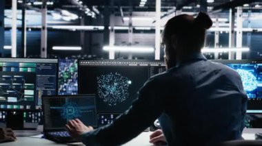 Veri merkezindeki cihazları kullanarak üretken yapay zeka yardımıyla kodlama yap. Bilgisayarda, laptopta ve tablette, kamera A 'da yapay zeka büyük dil modelleme teknolojisini denetleyen IT çalışanı.