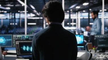 Veri merkezine gelen teknisyen, üretici yapay zeka yardımıyla kodlama yapıyor. BT uzmanı masada oturuyor, yapay zeka üzerinde çalışıyor büyük dil modeli çözme görevleri, kamera A