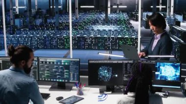 Veri merkezinde işbirliği yapan yazılım geliştiricileri, bilgisayardaki yapay zeka tanılarını gözden geçiriyorlar. Bilgi işlem personeli sunucu odasında tartışıyor, makine öğrenme sistemlerini optimize ediyor, kamera A