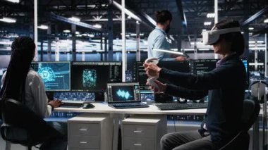VR gözlüklerini veri merkezinde kullanan programcı, üretici yapay zeka yardımıyla kodluyor. Sanal gerçeklik kullanan bir bilişim uzmanı, yapay zeka büyük dil modelini görevleri çözmesi için kullanıyor, kamera A