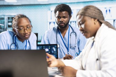 Afrika kökenli Amerikalı pratisyen hekim, genç bir tıbbi ekibe başkanlık ediyor. Röntgen görüntüleme sonuçlarını analiz ediyor ve doğru teşhis koyuyor. Revirdeki hemşireler ve doktorlar..