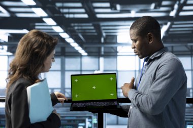 Veri merkezindeki mühendisler ağ virtüözleştirme için yeşil ekran dizüstü bilgisayar kullanıyorlar. Sunucu çiftliğindeki iş arkadaşları kroma anahtar defteri kullanıyor, depolama dizilerini güncelliyor, ayarlar doğrulanıyor