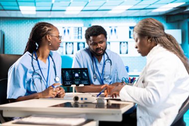 Afrika kökenli Amerikan tıp personeli, bir ofiste danışma öncesinde gelişmiş teknoloji araçlarıyla uzmanlıklarını birleştiriyor. Harika sağlık hizmetleri sunmak için ekip çalışması.