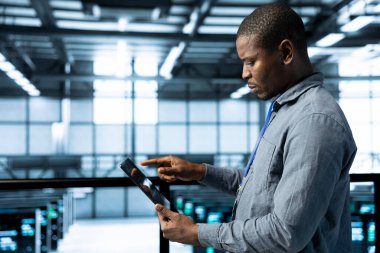 Veri merkezinde yeni sunucu mimarileri yerleştirmek için tablet kullanarak ağ viralizasyonunu yapılandırın. Sunucu odasındaki adam depolama dizilerini güncelliyor, istikrarlı performansı sürdürmek için ayarları doğruluyor