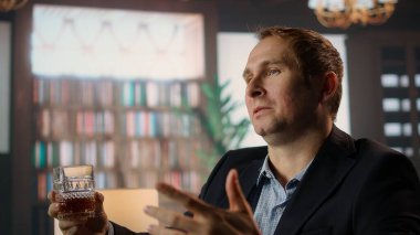 Seçkin bir sosyete üyesi, üst sınıf bir iş birliğinde bir ortakla karışık viski içerek görüşmeler yapıyor. Seçkin üst sınıf beyefendiler servet kazanıyor. Kamera A.