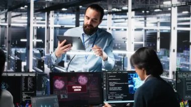 Veri Merkezi Yöneticisi, Yapay Zeka kullanırken kritik hatayı düzelten programcıları koordine ediyor. Sunucu odası lideri, yapay zeka ve kamera A 'yı kullanarak arızalı açılır pencereyi tamir eden işçilere nezaret ediyor.