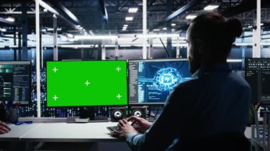 Sunucu odası teknisyeni yeşil ekranda yapay zeka kullanarak tanı koyuyor. Veri merkezinde bilişim işçisi, krom anahtar bilgisayarda yapay zeka kullanarak performans verilerini analiz ediyor, kamera A