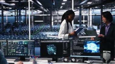 Veri merkezi mühendislerinden oluşan bir ekip evrakları inceliyor ve derin öğrenme algoritmalarını veri tabanlarını analiz etmek için kullanıyor. Çok ırklı sunucu çiftliğindeki çalışanlar yapay zekayı kullanarak veri kalıplarını ve kamera A 'yı tanıyorlar.