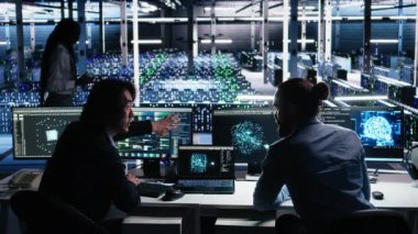 Veri merkezinde kıdemli programcı ve iş arkadaşı üretici yapay zeka yardımıyla kodlama yapıyor. Yapay zekaya baskı yapan takım arkadaşları görevleri çözmek için büyük dil modeli, kamera A