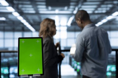 Sunucu odasının yanındaki tableti kapatın. Bilim adamları güvenlik denetimleri yapıyor ve hataları önlüyorlar. Yeşil ekran cihazı ve veri merkezinde meslektaşı olan Afrikalı Amerikalı bir adam.