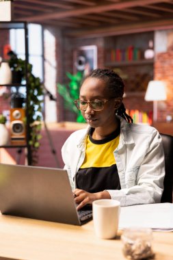 Öğrenci evde internette internette geziniyor, ödev yapıyor, internette bilgi araştırıyor. Apartmandaki Afrikalı Amerikalı kız okul işleri için dizüstü bilgisayarda makaleler okuyor.