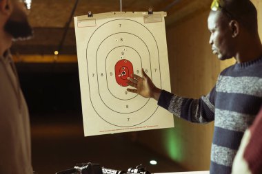 Atış poligonu güvenlik görevlisi müşterileri nasıl vuracağını gösteriyor. Menzil aktivitelerini denetliyor. Atış poligonu uzmanı silahlarla nasıl nişan alınacağını öğretiyor.