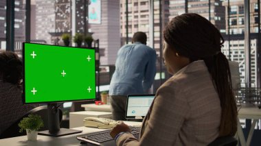 Ofis masasındaki işkadını, etkili karar verme mekanizmalarını ve şirket hedeflerini desteklemek için yeşil ekrana bakıyor, belgeler ve bilgi grafikleri okuyor. İdari görevler. Kamera B.