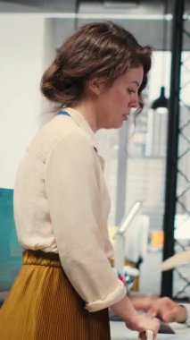 Ofisteki dikey Videocu Kadın sekreteri evrak ve raporlarla dolu bir yük arabasıyla bir meslektaşına dosya getiriyor ve kaynakların verimli bir şekilde dağıtılmasını sağlıyor. İdari görevler