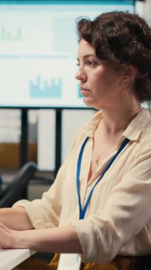 İşyerinde kulaklıkla şarkı dinleyen, şirketin verimliliğini ve verimliliğini sağlamak için idari görevleri yöneten dikey video kadın yönetici danışmanı. Kadın verileri gözden geçiriyor. Kamera.