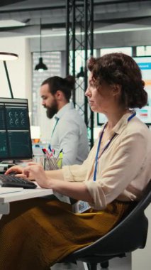 Üst düzey bir ofiste, bilgisayar monitöründeki performans ölçümlerini ve iş stratejisini analiz eden, rapor yazma ve sonuç ve başarı üzerine odaklanan dikey video kadın çalışanı