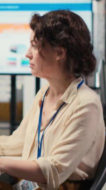 Üst düzey bir ofiste, bilgisayar monitöründeki performans ölçümlerini ve iş stratejisini analiz eden, rapor yazma ve sonuç ve başarı üzerine odaklanan dikey video kadın çalışanı