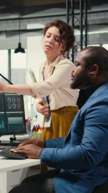 Aylık raporları tamamlamada birbirlerine danışan, iş verimliliğine ilişkin KPI veri içgörülerini gözden geçiren dikey video çok ırklı çalışma ekibi. Başarı için çalışanlar arası işbirliği. Kamera A.