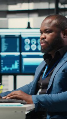Dikey Video Afrikalı Amerikalı erkek, finansal veri tahminlerini bilgisayarda analiz ediyor, şirket amaçlarıyla uyum sağlamak için yenilikçi iş çözümleri geliştiriyor. Profesyonel çevre