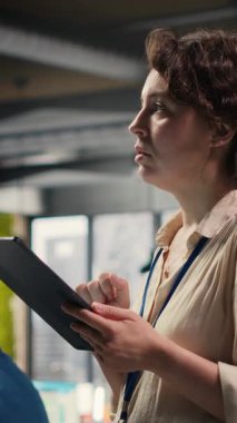 Dikey Videolu Dalgın Kadın İş Lideri, çok uluslu bir şirkette çalışırken, ofisinde tabletine ilişkin tahminler yapıyor. Geliştirme vizyonu için veri analizi ve içgörüleri kullanan uzman