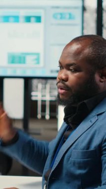 Dikey Video Siyah işadamı, yoğun çalışma nedeniyle sırt ve boyun ağrısına karşı, çalışma yerindeki kötü duruşunu düzeltiyor. Verimlilik ve verimlilik görevlerini çözen yönetici