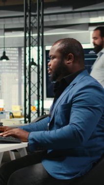 Dikey Video Afrikalı Amerikalı ofis çalışanı analitiği koz olarak kullanıyor ve stratejik hedeflere ulaşılmasını sağlamak için yazma ve aylık performans sonuçları, kaynaklar ve içgörüler raporluyor