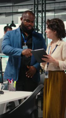 Dikey Video Çeşitli işçiler ekibi büyüme stratejisini geliştirmek için dijital araçlar ve analizler kullanır, modern bir ofiste yenilik ve kalkınmayı hızlandırmak için tablet üzerindeki finansal görüşleri gözden geçirir