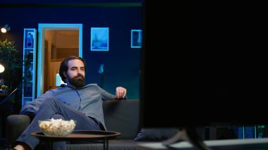 Odaya giren, patlamış mısır yiyen ve yayın servisiyle ilgili ilginç bir film izleyen adam, tatilin tadını çıkarıyor. TV 'de yayınlanan filmlere bakmak için eve gelen ve abur cubur yiyen kişi, kamera B