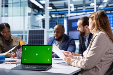 Endüstriyel fabrika çalışanları, kroma anahtar defteri kullanarak teknik darboğazları tanımlıyorlar. Fabrika ofisindeki ekip çalışanları verileri analiz ediyor, sistem sağlık ölçümlerini model dizüstü bilgisayarla inceliyor.