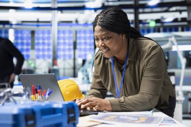 Güneş paneli santralindeki bilgisayar görüşünü inceleyen kadın mühendis geliştirme hedefleri için üretim fabrikası üretimini sağlamak için enerji sistemlerinin değerlendirmelerini yürütüyor..