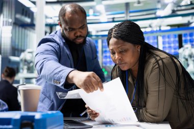 Fabrika mühendislerinden oluşan çok ırklı bir grup iş kıyafetleri kontrol ekipmanları ve üretim süreçleri, güneş paneli altyapısında profesyonel takım çalışması ve denetim gösterileri.