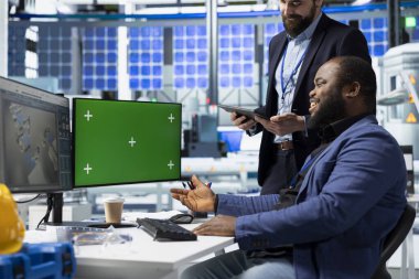 Danışmanlar ve fabrika analistleri, güneş paneli fabrikasında her detayı temiz enerji verimliliği ve güneş teknolojisi yeniliğiyle aynı hizaya getirmek için bir kopya ekran üzerinde çalışıyorlar..