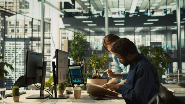 Ofisteki çalışanlar yönetimden proje evraklarını alıyor, yeni proje üzerinde çalışmaya başlıyorlar. Yönetici işçiye görevler veriyor, gerekli belgeleri sağlıyor, kamera B