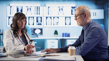 Sağlık uzmanı, eski hastasıyla rutin bir kontrol sırasında oksijen doygunluğunu ölçer ve hayati belirtileri kontrol eder. Sıhhiyeci doğru okumalar için oksimetre kullanıyor. Kamera A.