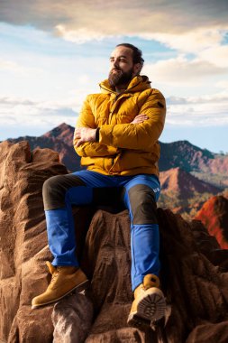 Genç maceraperest tepeden manzaralı bir dağ manzarasına bakarak doğanın yalnızlığını ve temiz havasını kucaklıyor. Farkındalık ve keşif hissi..