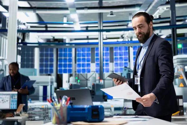 Solar Tech uzmanı tesisteki alternatif enerji sistemlerini değerlendiriyor, üretim hattını ve fotovoltaikleri yönetiyor. Temiz enerji ve endüstriyel işlemler verimliliği.