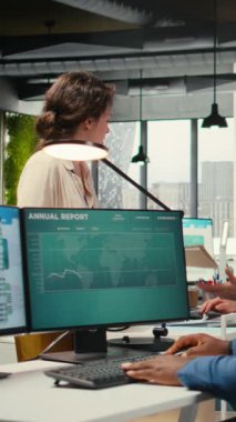 Ofisteki dikey Videocu Kadın sekreteri evrak ve raporlarla dolu bir yük arabasıyla bir meslektaşına dosya getiriyor ve kaynakların verimli bir şekilde dağıtılmasını sağlıyor. İdari görevler