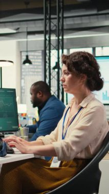 İşyerinde kulaklıkla şarkı dinleyen, şirketin verimliliğini ve verimliliğini sağlamak için idari görevleri yöneten dikey video kadın yönetici danışmanı. Kadın verileri gözden geçiriyor. Kamera.