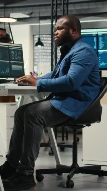 Dikey Video Afrikalı Amerikalı erkek, finansal veri tahminlerini bilgisayarda analiz ediyor, şirket amaçlarıyla uyum sağlamak için yenilikçi iş çözümleri geliştiriyor. Profesyonel çevre