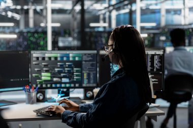 BT veri merkezinde ses kulaklığı takan bir uzman müşterilere teknik destek veriyor, sorun giderme hataları yapıyor. Sunucu çiftlik çalışanı müşteriler tarafından istenilen operasyonel teknik müdahaleleri yapıyor