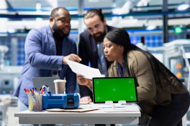 Profesyonel mühendislik grubu kroma anahtarının yanındaki güneş panellerini inceleyerek yeşil teknoloji ve çevre dostu yenilenebilir enerjide birlik gösteriyor. Üretim endüstrisinde operasyonel liderlik.