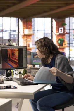 Kadın geliştirici, bilgisayar üzerinde sanal yapay zeka asistanı ile bir oyun merkezi tasarlamak için etkileşime girer, bir bilim kurgu video oyunu için geleceksel uzay istasyonu tasarımları oluşturmak için otomasyon ve makine öğrenme kullanır..