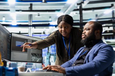 Profesyonel usta mühendisler kontrol panellerini inceliyor ve verileri analiz ediyor ve bir güneş enerjisi üretim tesisinde bilgi paylaşımı yapıyor. Teknik içgörü ve grup işbirliği.