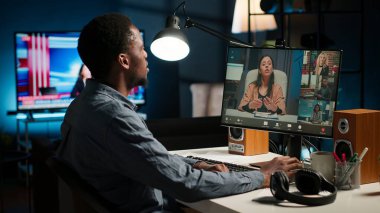 Afrikalı Amerikalı erkek serbest çalışan, bilgisayarında iş arkadaşlarıyla çevrimiçi bir tartışmaya girdi ve web 'de bir konferansa katıldı. Siyahi adam bilgisayardaki iş arkadaşlarıyla telefonda video konferansı yapıyor. Kamera B.